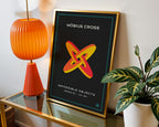 Möbius cross print displayed beside an orange lamp and houseplant